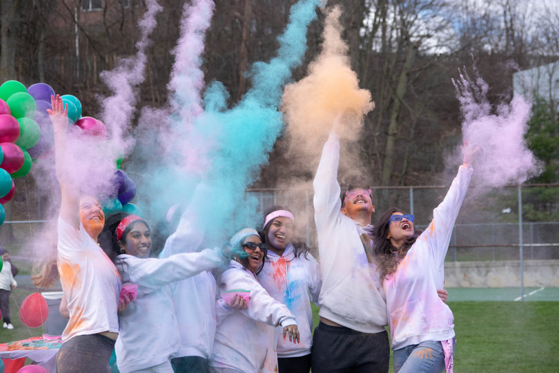 Holi participants throwing powder in the air.