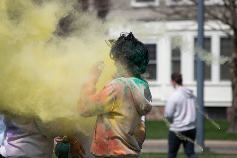 A Holi participant is surrounded by flying Holi powder.