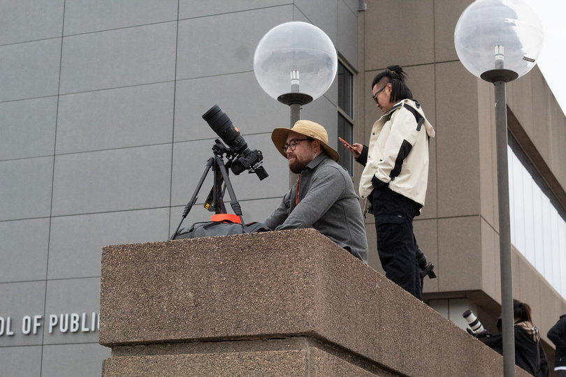 A man looks at his camera that is pointed to the sky.