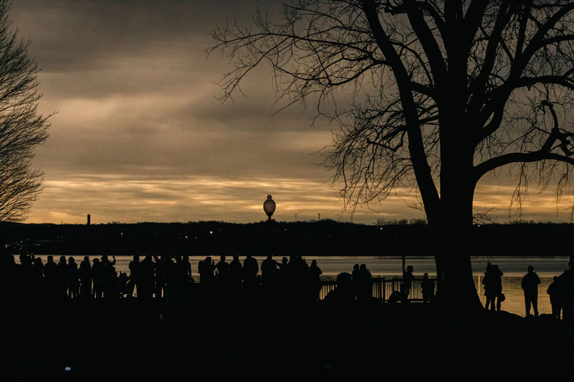 A crowd gathers by the water.
