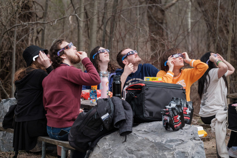 A group of people look up at the sky.