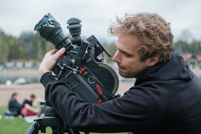 A man points a camera at the sky.
