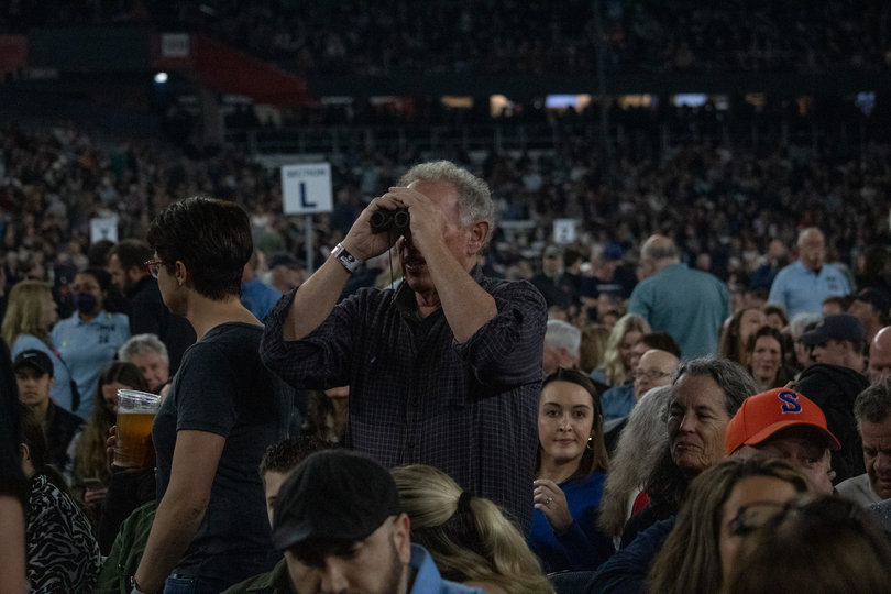 Man looking through binoculars towards the stage