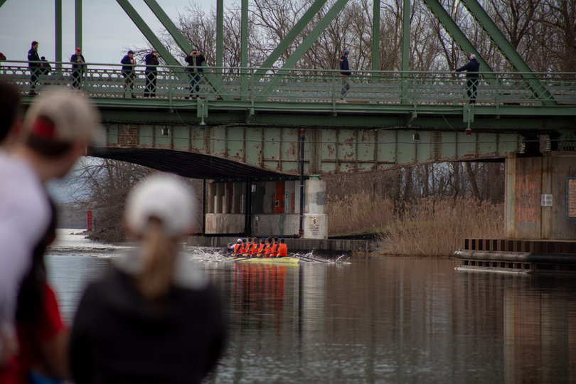 2 people watching the syracuse varsity 8 on the water