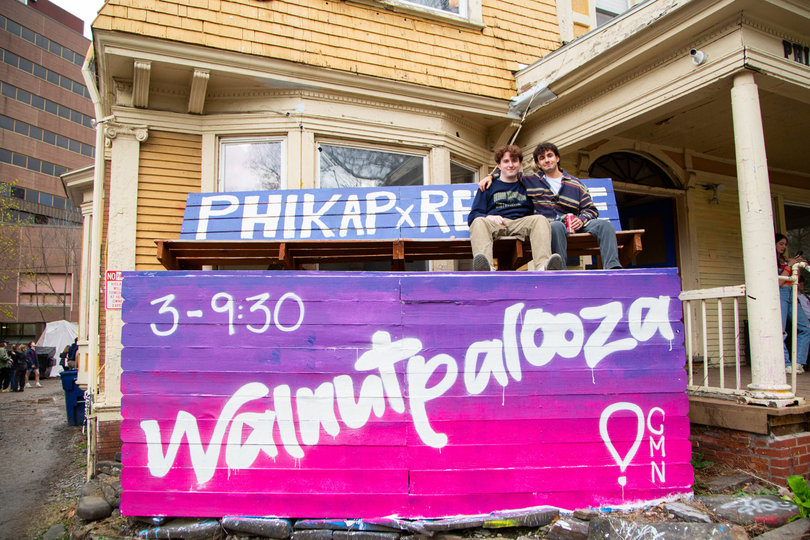 Two people sitting on top of a bench that says Walnutpalooza