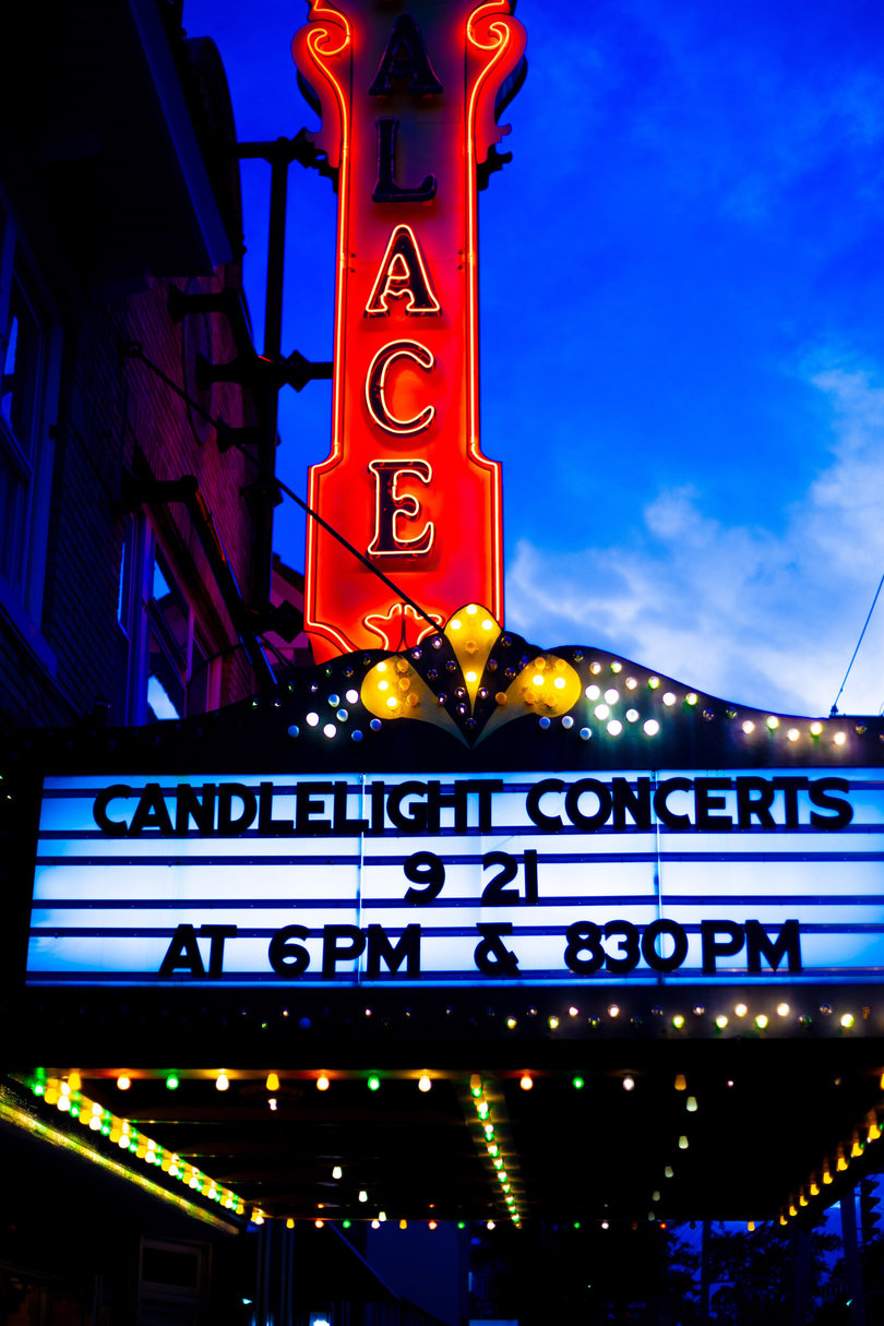 A neon sign illuminates the Palace Theatre’s facade, displaying the night’s shows. After the shows, the sign casts a red hue across the front walk.
