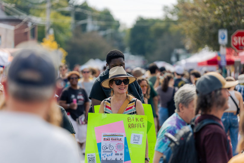 A representative from the Syracuse Peace Council advertises a bike raffle to garner donations. The Syracuse Peace Council has advocated for peace and social justice since 1936.
