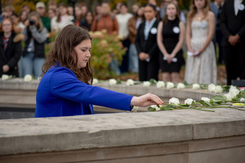 A person placing a flower on top of a wall