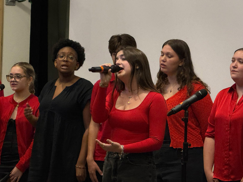 A group of people on stage. One person is singing.