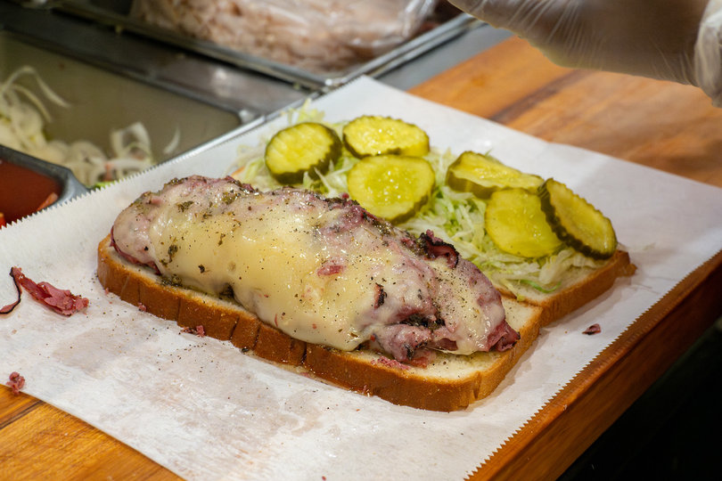 A Brooklyn Pickle employee prepares a sandwich at the shop in East Syracuse. Sandwich prep is a speedy process, with day staff able to make a sandwich in 30 seconds.
