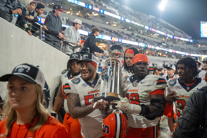 Josh Ilaoa and David Omopariola carry the Holiday Bowl trophy into the tunnel after Syracuse’s victory. The triumph for the Orange was their 10th of the season, marking the third 10-win season this century.