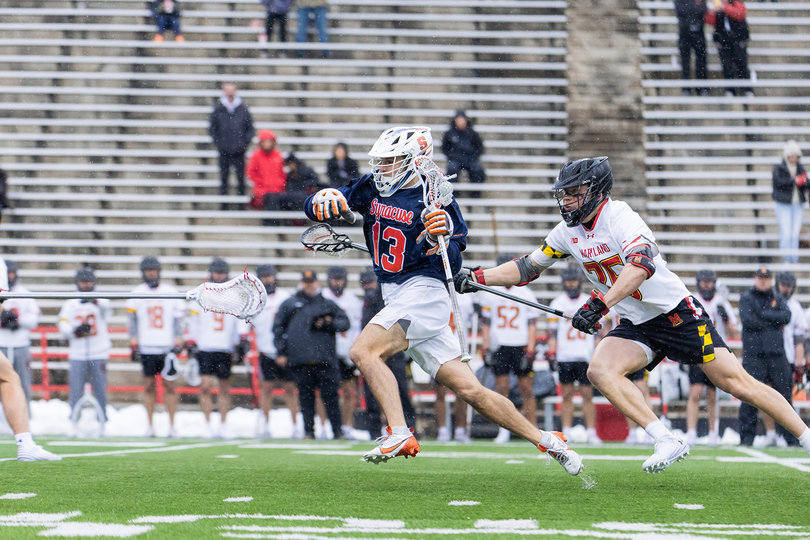 Syracuse midfielder Tyler McCarthy (pictured, No. 13) slices toward the cage after weaving past Maryland long-stick midfielder AJ Larkin (pictured, white jersey). The Orange struggled all afternoon against the Terrapins to materialize scoring chances close to the net. 