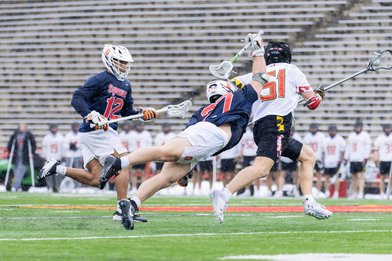 SU faceoff man John Mullen (pictured, No. 27) dives, fully extending his body while rearing his stick back to poke the ball from the stick of Maryland’s Jack McDonald (pictured, No. 51). McDonald picked up a game-high seven ground balls to help the Terrapins control time of possession over the Orange.