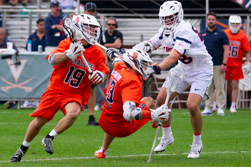 Sophomore midfielder Wyatt Hottle (left) cradles the ball in his stick while dodging downfield against Virginia’s defense, while UVA defenseman Luke Hublitz (right) shoves SU midfielder Tyler McCarthy. Syracuse and Virginia met for a physical battle on Saturday, a regular occurrence in the ACC rivalry.