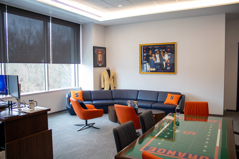 SU head coach Fran Brown’s office includes a couch, a photo of him and his family, jerseys of former SU players who had NFL careers and a table with the JMA Wireless Dome’s field outline on it.