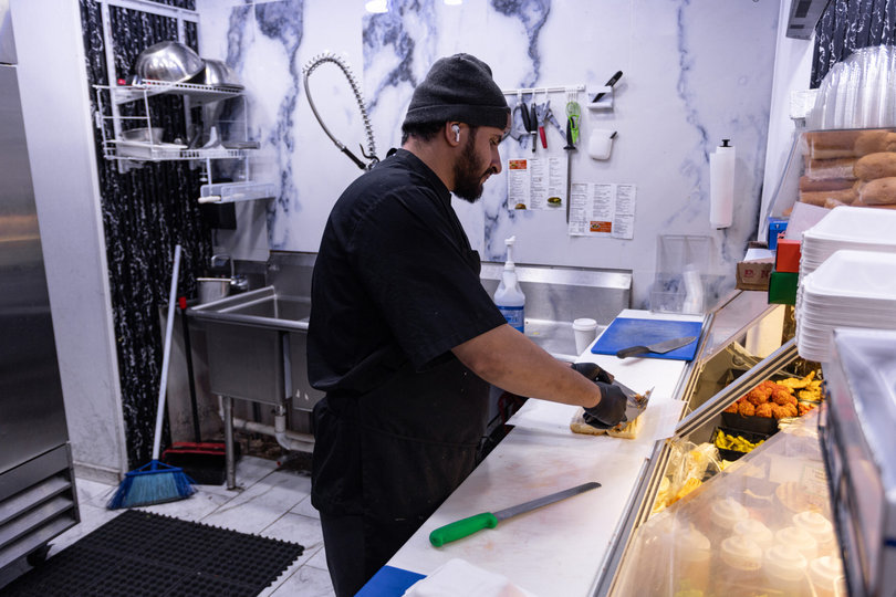 A chef prepares “The Godfather,” a specialty chapata at Cuse Gourmet Deli and Café. The sandwich consists of hot roast beef, turkey, melted provolone, grilled onions and mayo atop a toasted hero.
