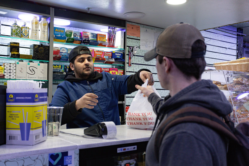 A customer picks up his late-night order. Cuse Gourmet Deli and Café is the sole option serving food throughout the night on Marshall Street.