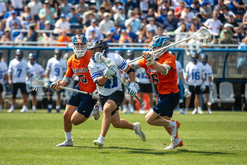 While Duke faceoff man Cal Girard (No. 41) cradles the ball, he’s swarmed by Syracuse’s Sam English (left) and Chuck Kuczynski (right). Syracuse forced just five turnovers against Duke, allowing the Blue Devils to get off 45 shots.
