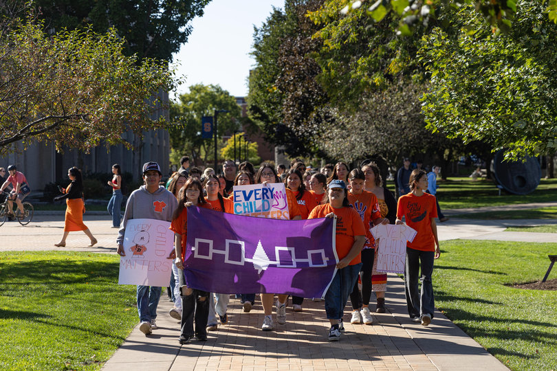 Demonstrators walk past Carnegie Library, drawing attention from SU community members passing by the area.