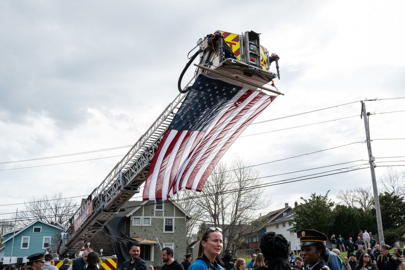 Firefighters hold a flag above the crowd gathered for the monument’s reveal. Several attendees, including members of the police force, family and friends of the officers, were present for the unveiling.