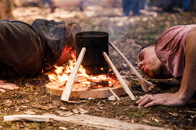 Kennon Gardner and Dziergas practice fire building, a doubles event. After building a small log cabin fire, they use their breath to keep the flame underneath the can until water inside boils over.
