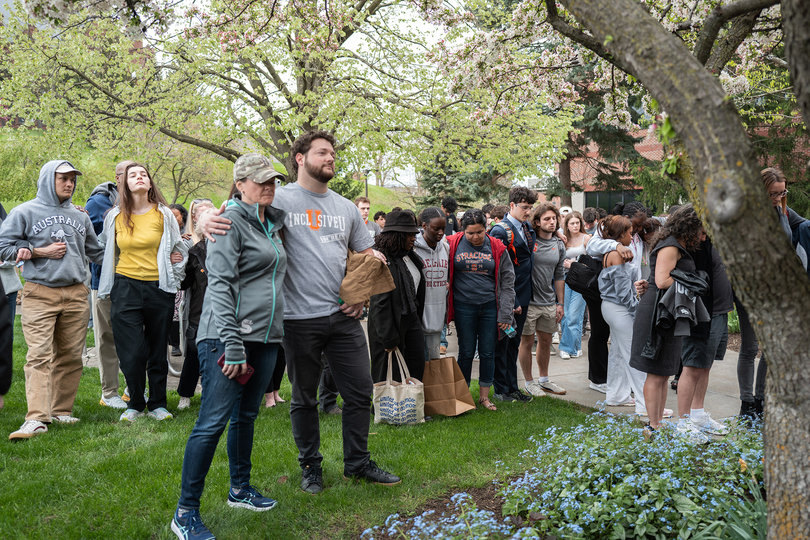 Attendees of the “Go Gray in May: Brain Cancer Awareness Month Walk” gather in prayer for outgoing Chancellor Kent Syverud’s recent brain cancer diagnosis outside Crouse-Hinds Hall. Hendricks Chapel Rev. Devon Bartholomew shared remarks with the group after Student Government Association members introduced him.