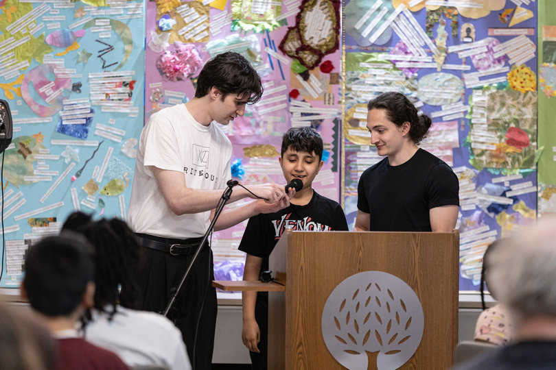 Jacob Gedetsis (left) holds the microphone for a Write Out student to share a poem he wrote. Write Out was inspired by a class Gedetsis took at Syracuse University where he taught writing workshops to children.