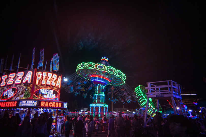 Attendees of the Great New York State Fair ride a neon-lit swing. At this year’s Fair, visitors could enjoy rides, concessions like pizza and nachos and live concerts.