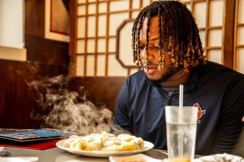 Syracuse linebacker Garvin St. John looks over a plate of pork dumplings at Yang Di Chun BBQ in Syracuse. St. John has gained over 290,000 Instagram followers through speaking Mandarin, often at traditional Chinese restaurants in Syracuse.