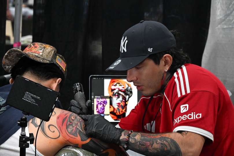 One of many artists at the Villain Arts Tattoo Festivals tattooing a snake sleeve on a patron. The Villain Arts Tattoo Festivals were founded in 1999 by Troy Timple.