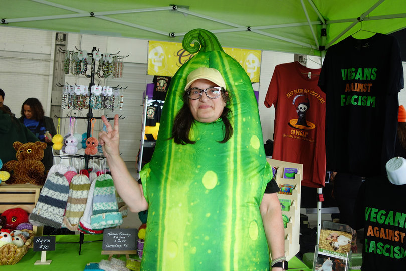 Dressed as a cucumber, Christine Volk throws up a peace sign at Syracuse Vegfest. Volk and Sam Kenney host "Compassion & Cucumbers," a podcast that discusses topics related to the vegan community.