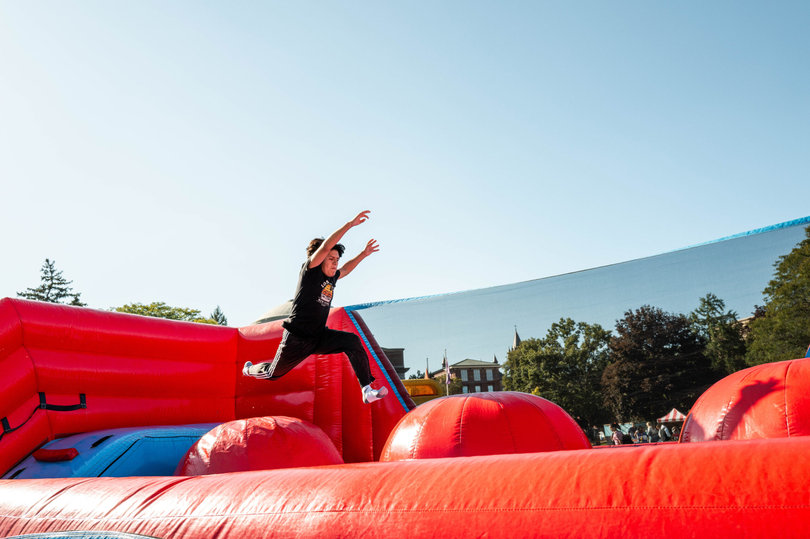 A student leaps in the air on an inflatable obstacle course at Quad-A-Palooza. The event also offered food trucks and live music from student DJs.