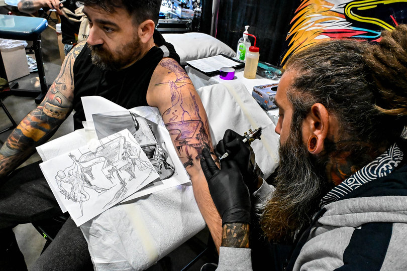 An artist at Syracuse’s Villain Arts Tattoo Festivals tattoos a piano on a patron. The three-day convention at the Oncenter Convention Center brought over 300 tattoo artists.  